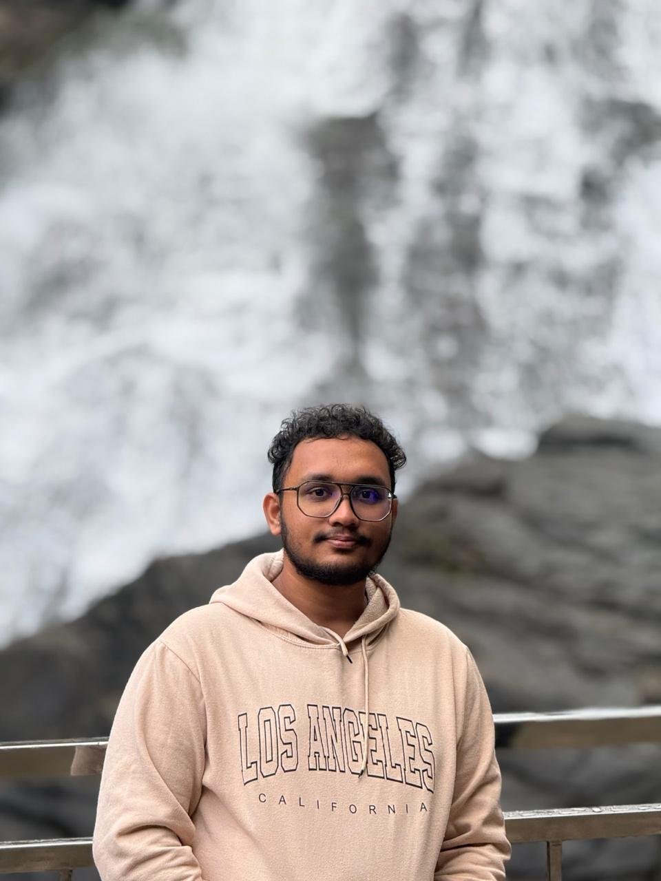 Ubaid in a beige hoodie near a waterfall